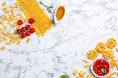 Photo of Beautiful composition with raw pasta and ingredients for sauce on marble background, top view