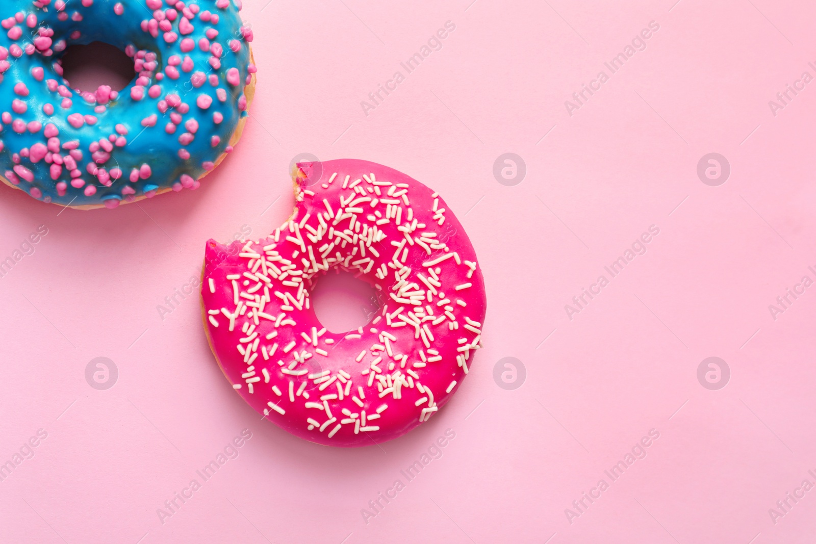 Photo of Delicious glazed doughnuts on color background, top view