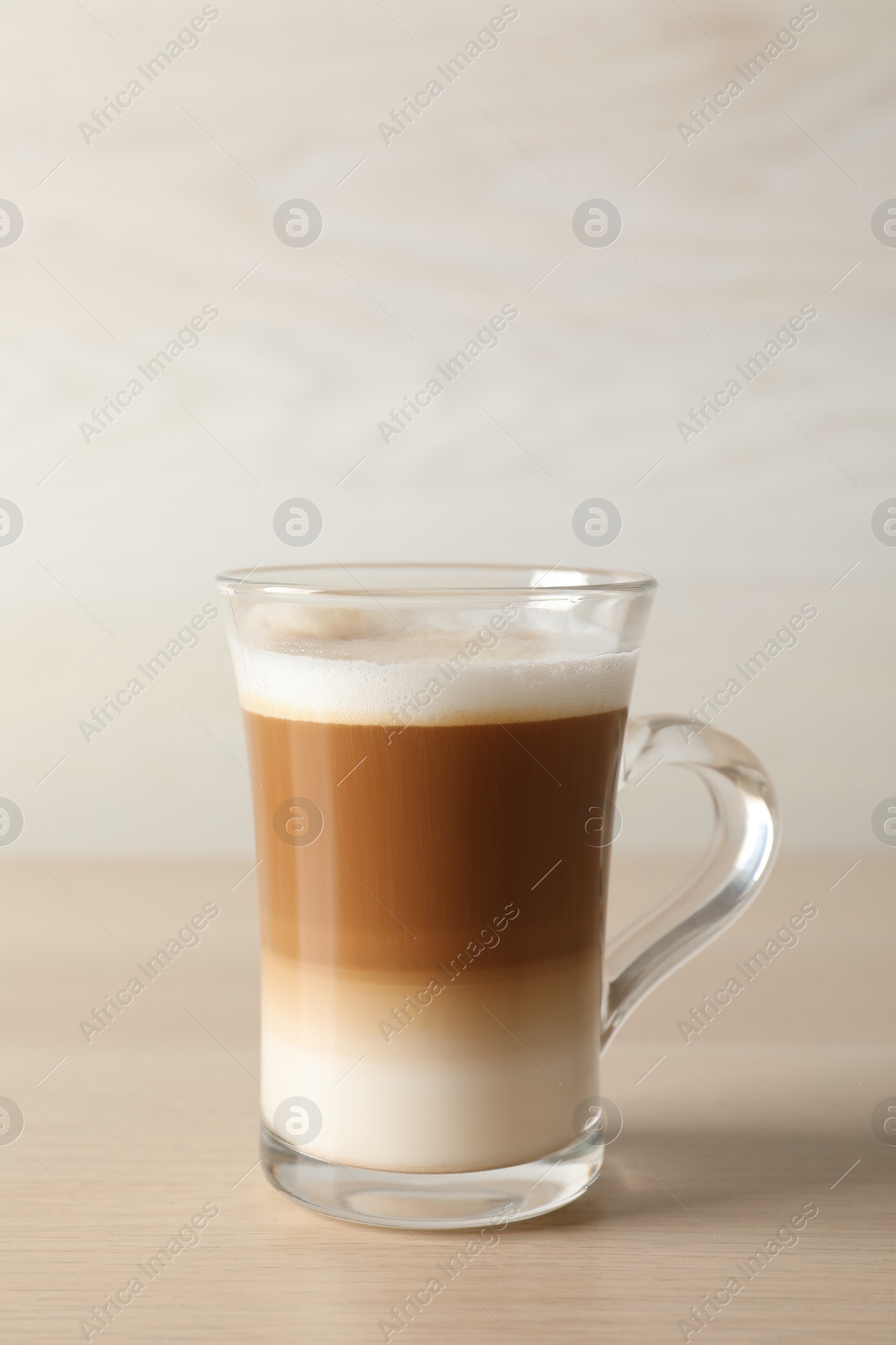 Photo of Hot coffee with milk in glass cup on wooden table