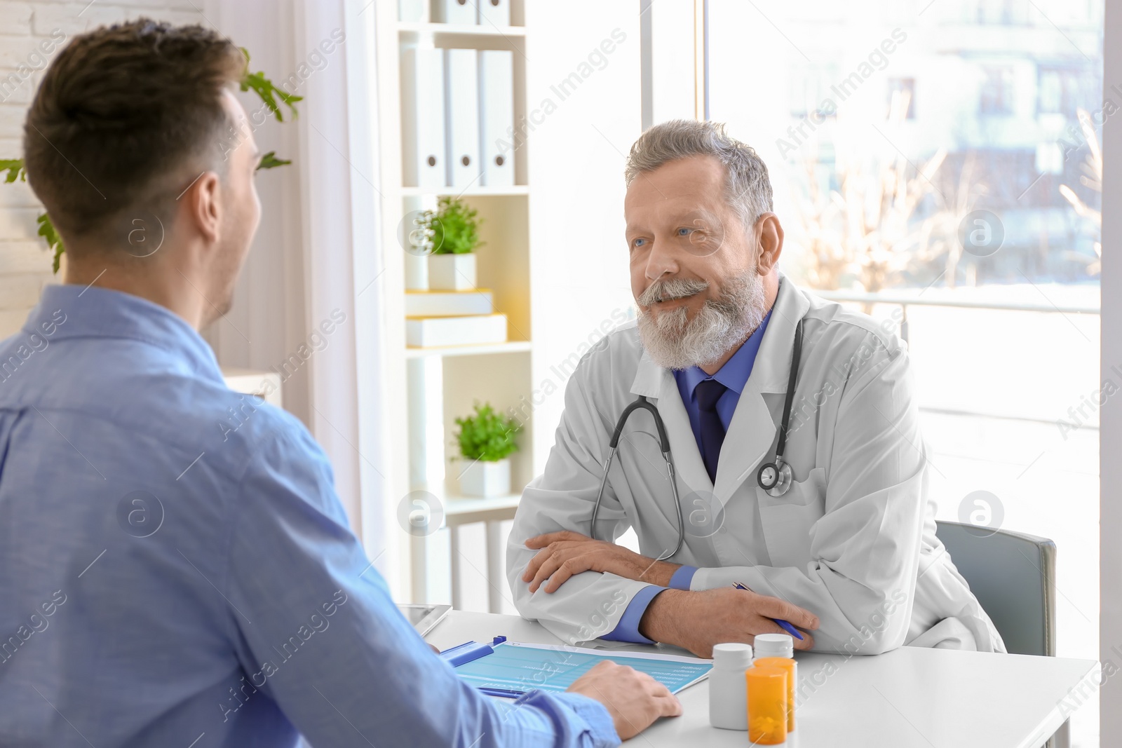 Photo of Mature doctor consulting patient in clinic