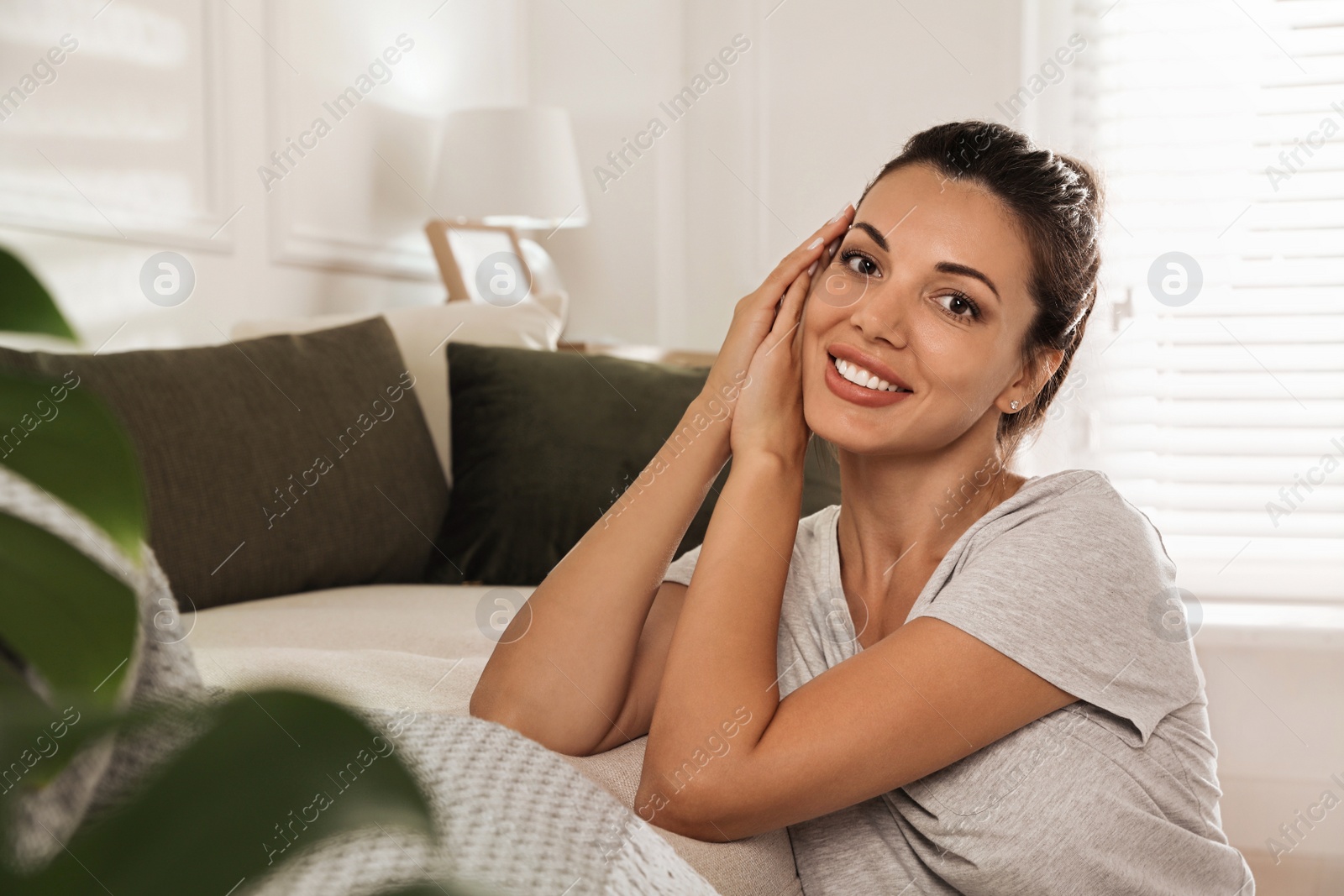 Photo of Happy beautiful woman near sofa at home