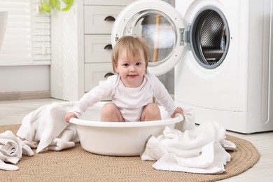 Photo of Little girl among baby clothes in bathroom