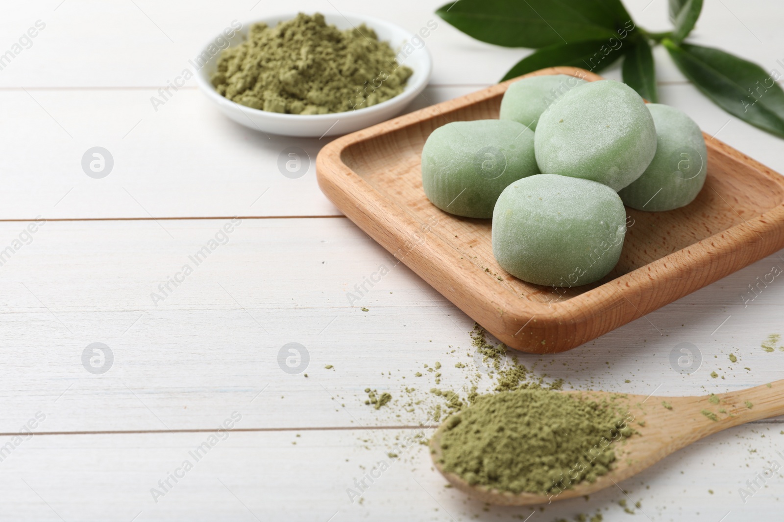 Photo of Delicious matcha mochi on white wooden table, space for text