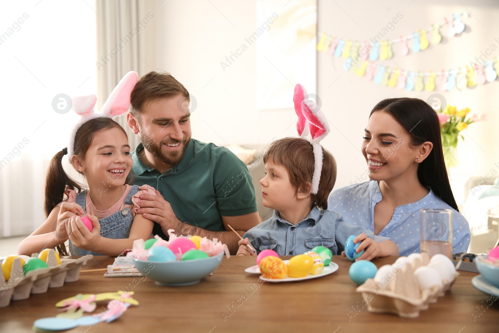 Photo of Happy family painting Easter eggs at table indoors