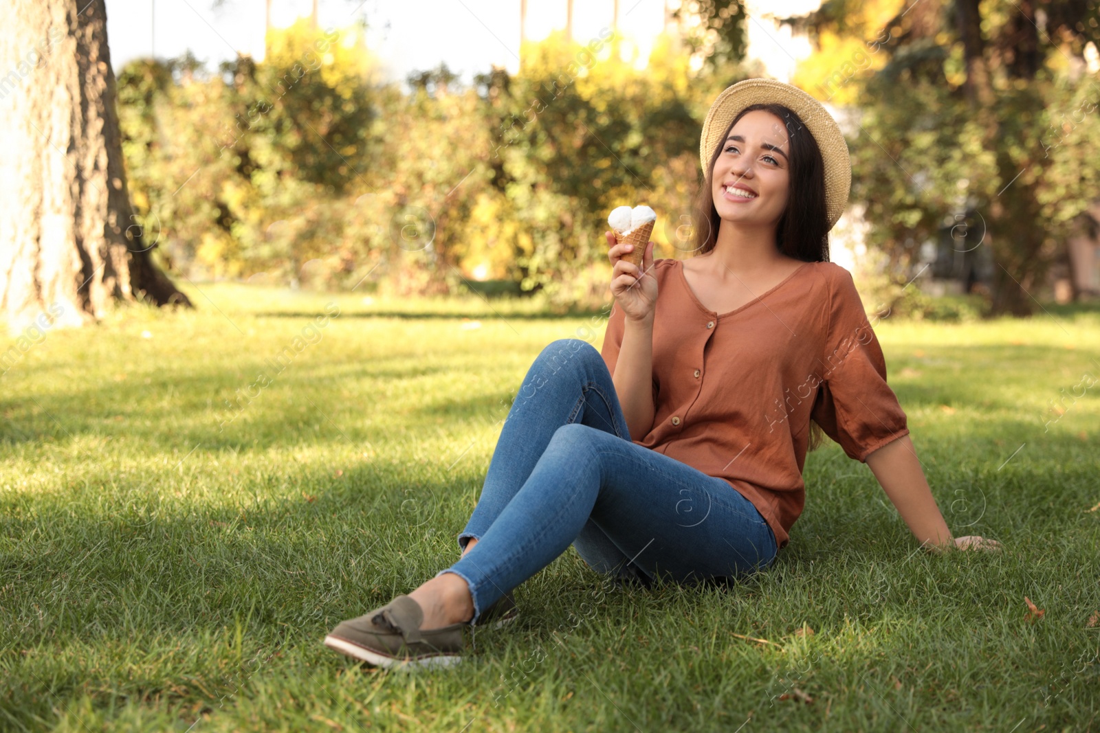 Photo of Happy young woman with delicious ice cream in waffle cone outdoors