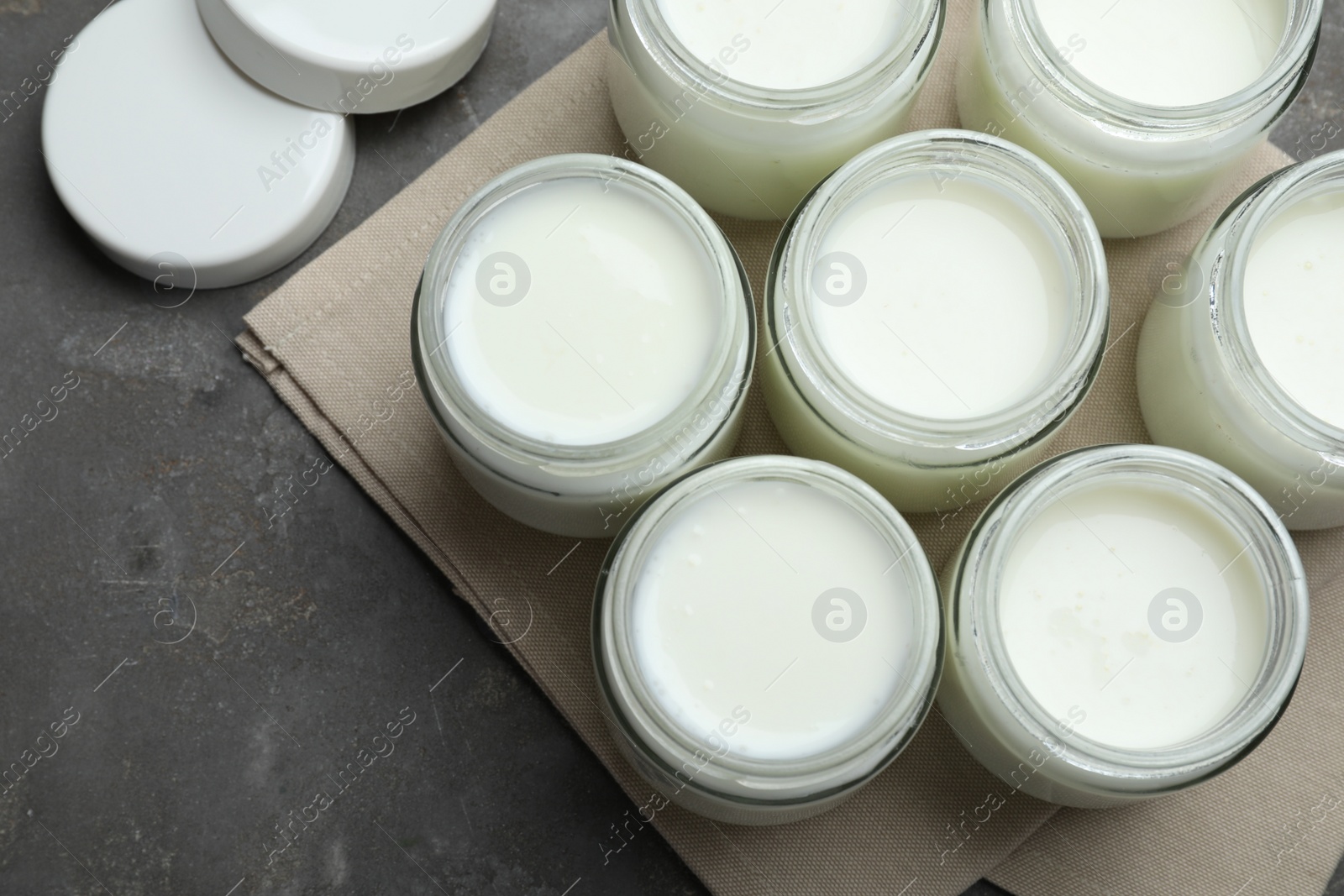 Photo of Tasty yogurt in glass jars on grey table, flat lay