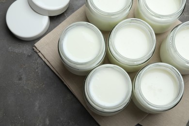 Tasty yogurt in glass jars on grey table, flat lay