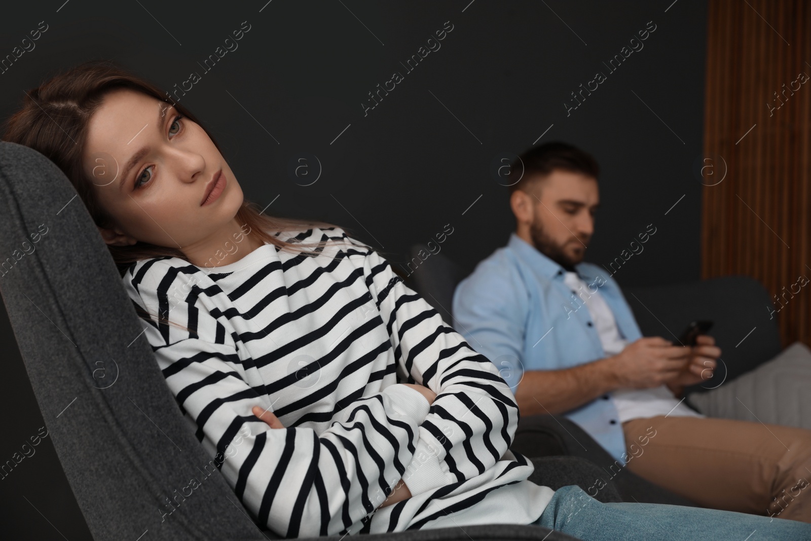 Photo of Man preferring smartphone over his girlfriend at home, focus on woman. Relationship problems