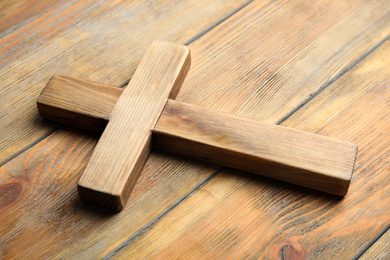 Christian cross on wooden background, closeup. Religion concept