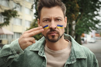 Photo of Angry man with drawingsUkrainian flag on city street
