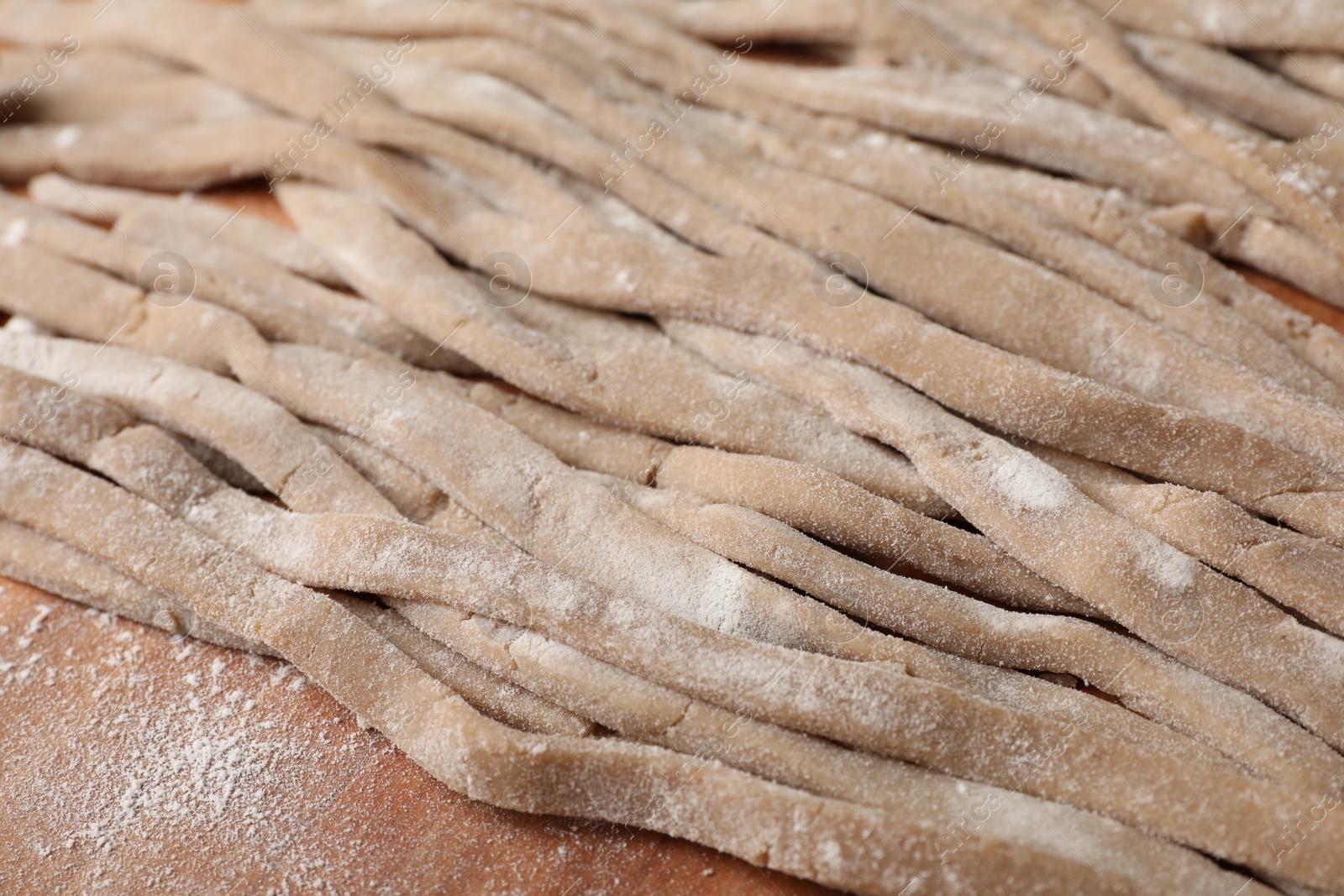 Photo of Uncooked homemade soba (buckwheat noodles) on wooden table, closeup