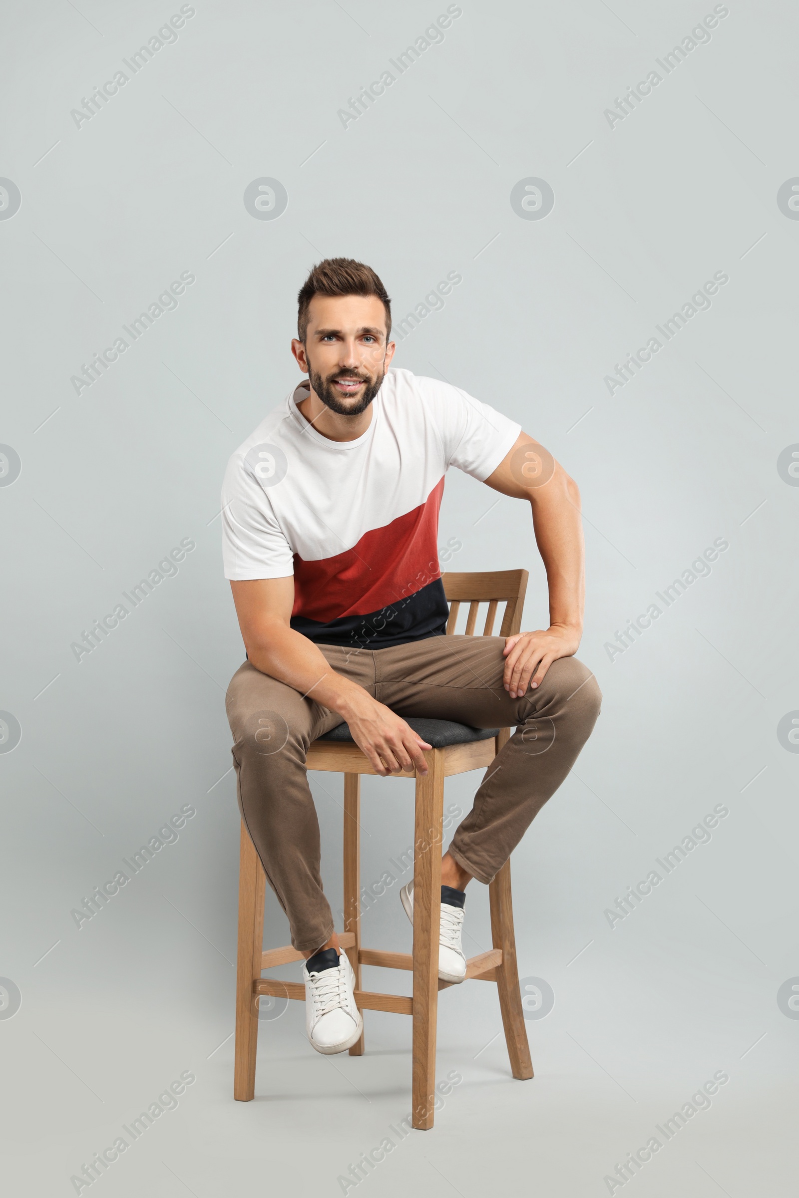 Photo of Handsome man sitting on stool against light grey background