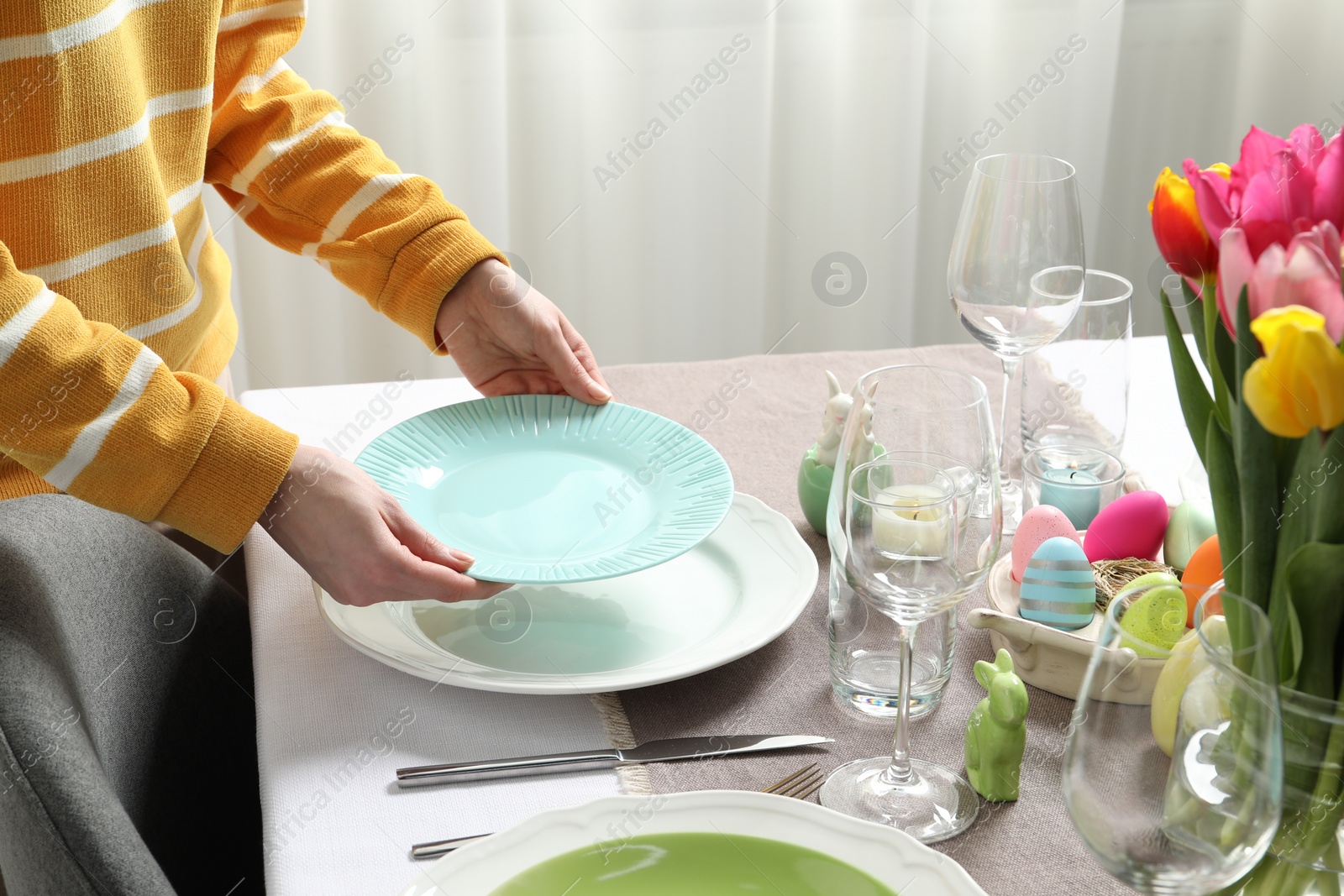 Photo of Woman setting table for festive Easter dinner at home, closeup