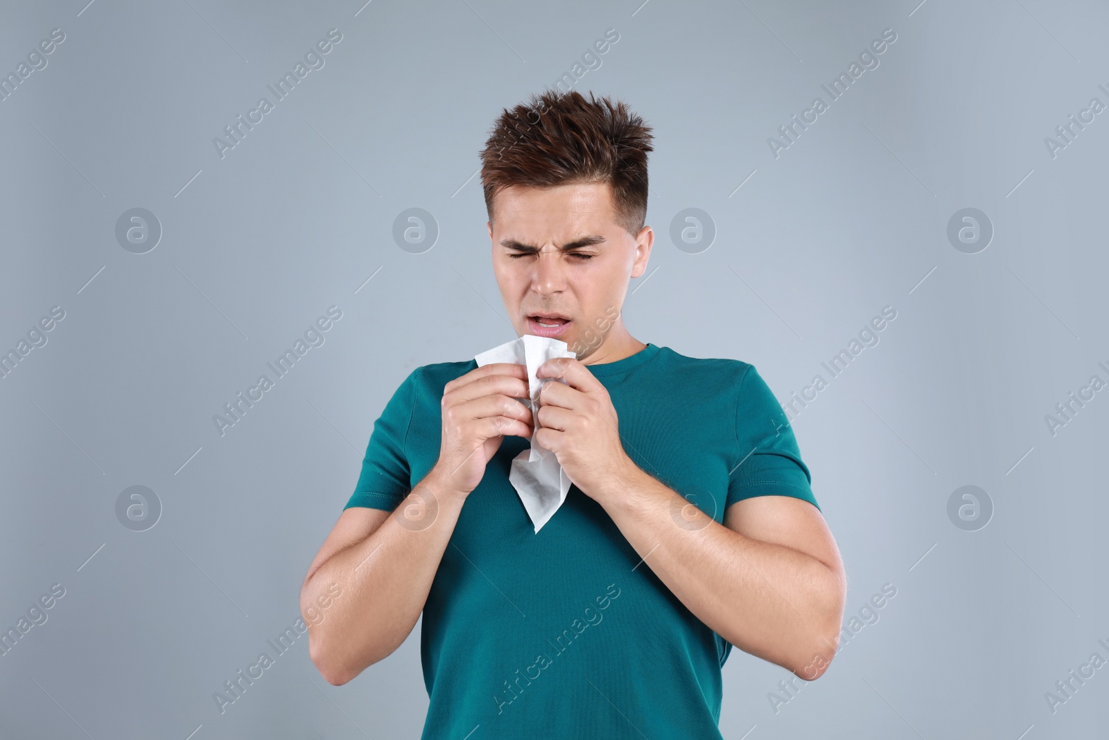 Photo of Young man suffering from allergy on grey background