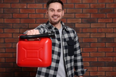 Man holding red canister against brick wall, selective focus