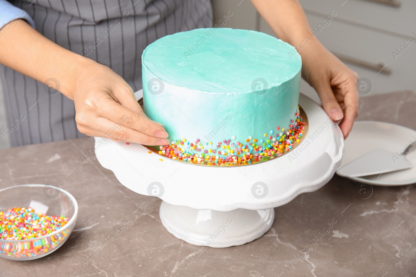 Photo of Woman decorating fresh delicious birthday cake in kitchen, closeup