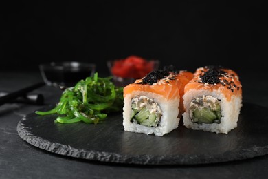 Photo of Delicious sushi rolls and chuka on black slate table
