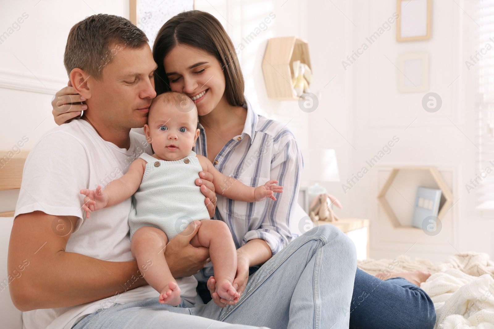 Photo of Happy family with their cute baby on bed at home