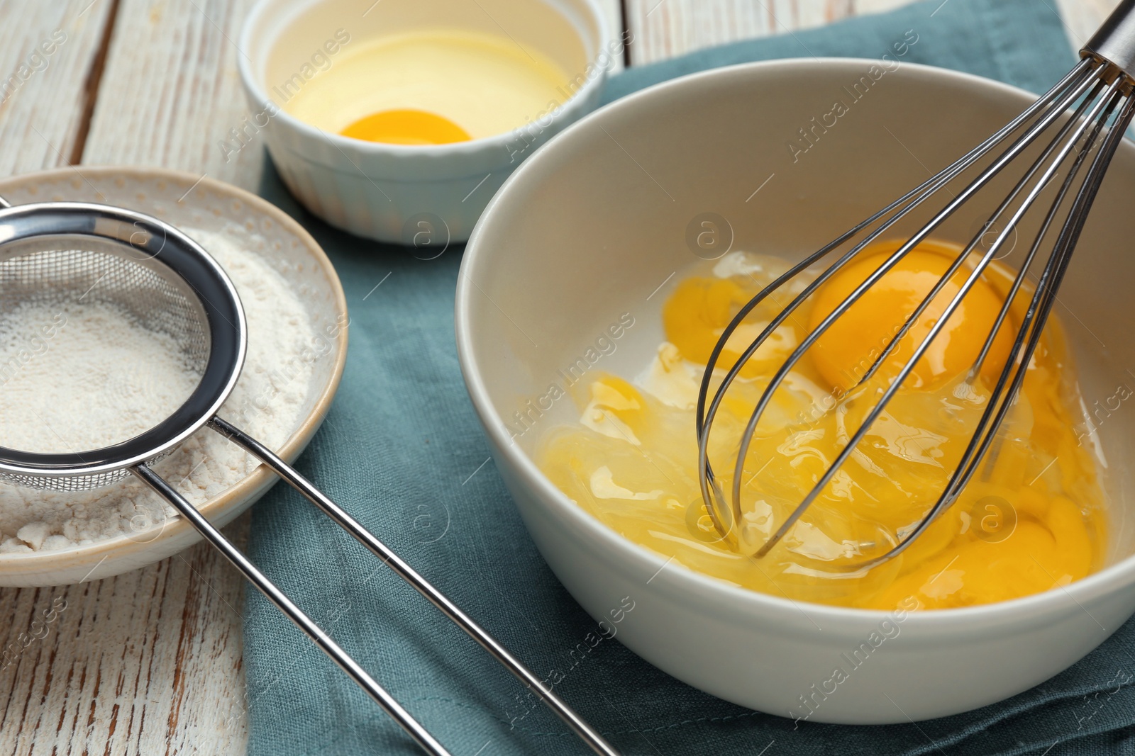 Photo of Whisking eggs in bowl on wooden table, closeup