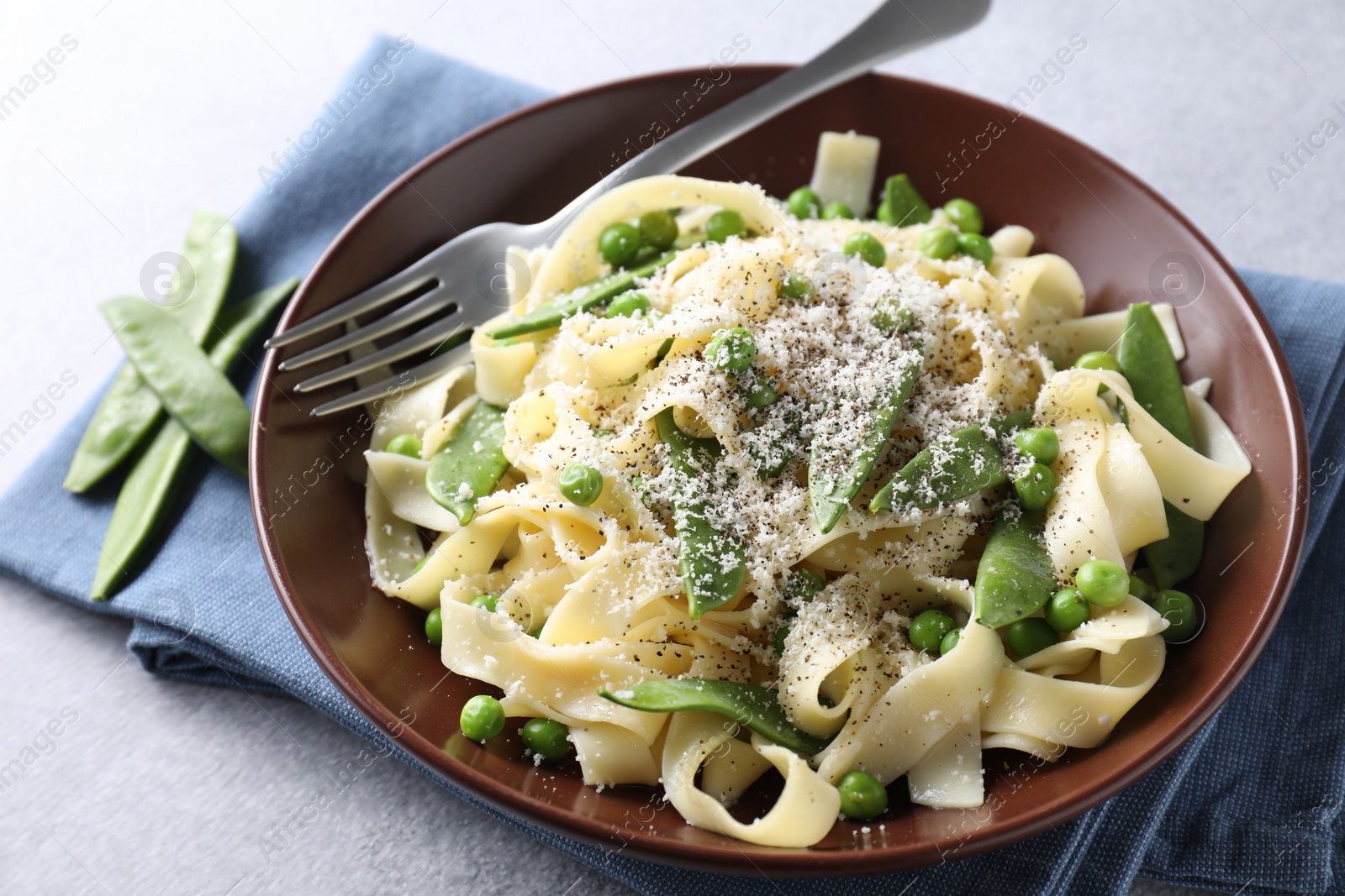 Photo of Delicious pasta with green peas and cheese served on grey table