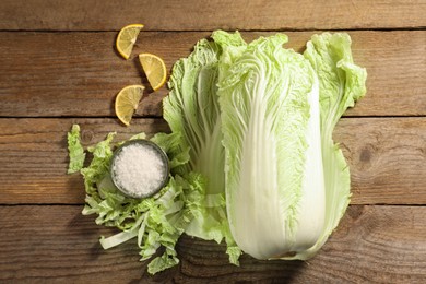 Photo of Fresh Chinese cabbage, salt and lemon on wooden table, flat lay