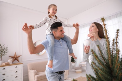 Photo of Happy family with cute child decorating Christmas tree at home