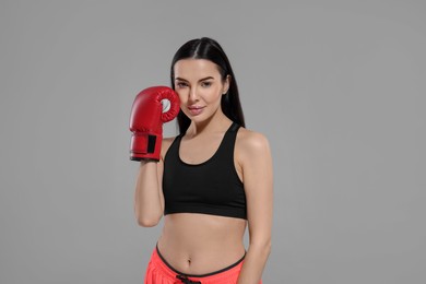 Portrait of beautiful woman in boxing gloves on grey background