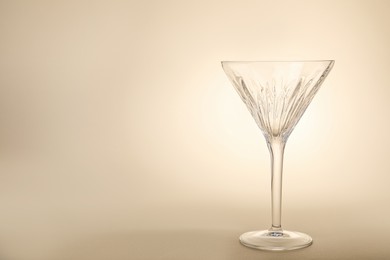 Photo of Elegant empty martini glass on beige background. Space for text