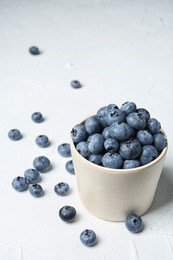 Crockery with juicy and fresh blueberries on white table