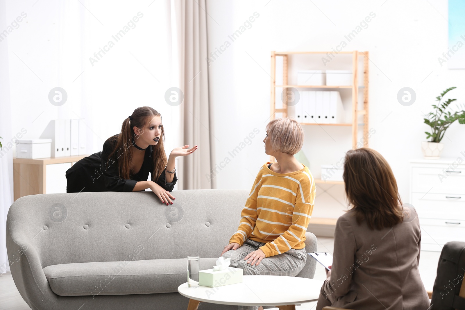 Photo of Psychotherapist working with teenage goth girl and her mother in office