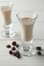 Coffee cream liqueur in glasses and beans on white wooden table