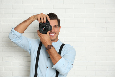 Photo of Professional photographer working near white brick wall in studio. Space for text