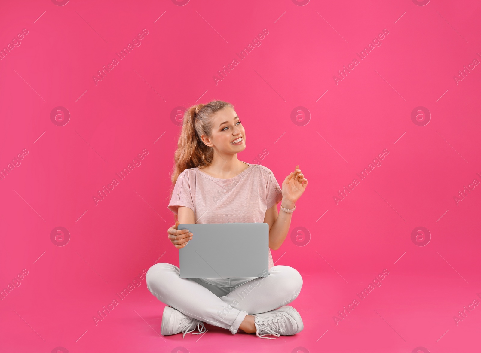 Photo of Beautiful young woman with laptop on pink background