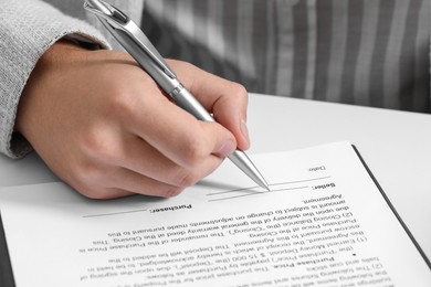 Photo of Man signing document at white table, closeup