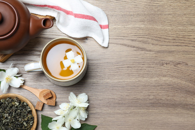 Flat lay composition with tea and fresh jasmine flowers on wooden table. Space for text