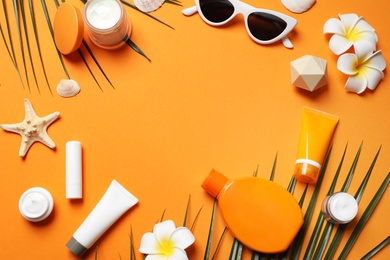 Photo of Flat lay composition with sun protection cosmetic products on orange background, space for text