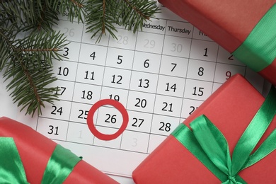 Photo of Gifts on calendar with marked Boxing Day date, flat lay