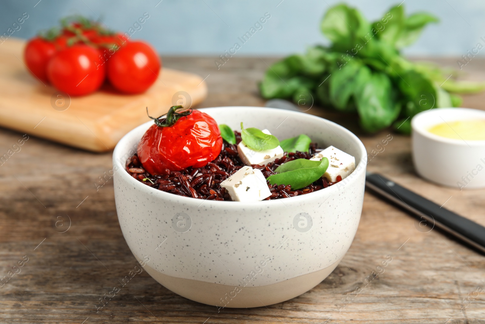 Photo of Bowl with delicious cooked brown rice on wooden table