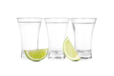 Shot glasses of vodka with lime slices on white background