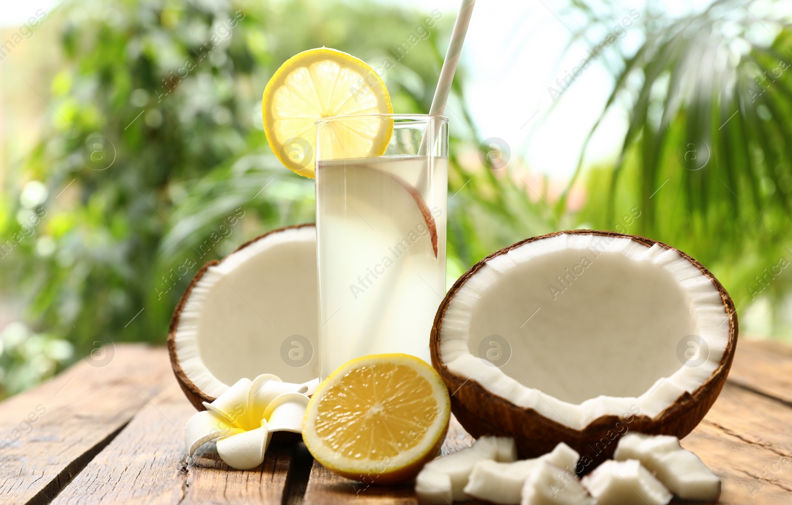 Photo of Composition with glass of coconut water and lemon on wooden table