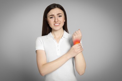 Image of Arthritis symptoms. Young woman suffering from pain in wrist on light grey background