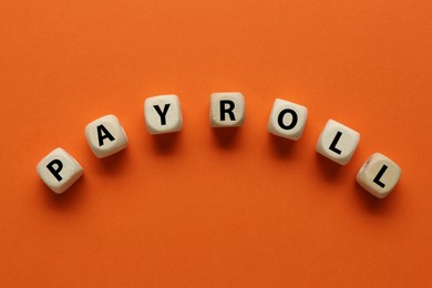 Word Payroll made of wooden cubes with letters on orange background, flat lay