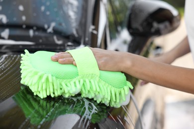 Woman washing car with sponge outdoors, closeup