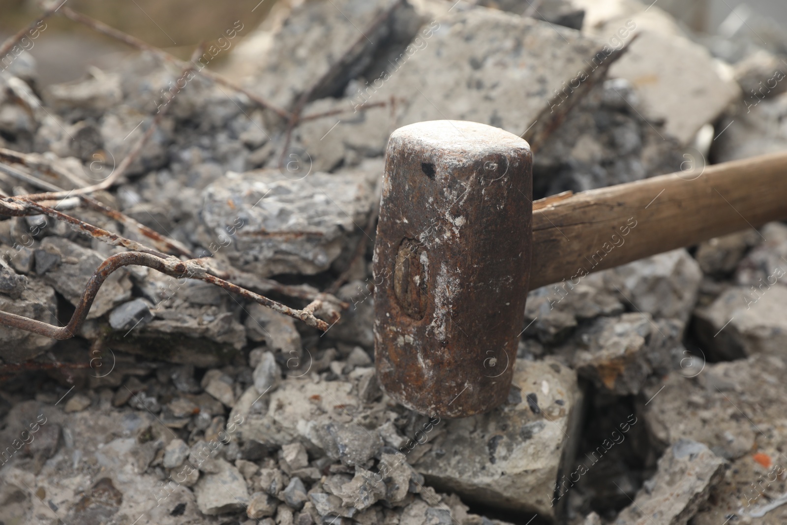 Photo of Sledgehammer on pile of broken stones outdoors, closeup