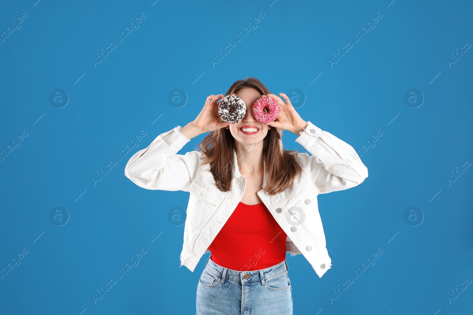 Photo of Beautiful young woman with donuts on blue background