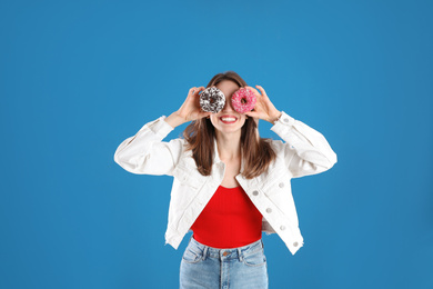 Beautiful young woman with donuts on blue background