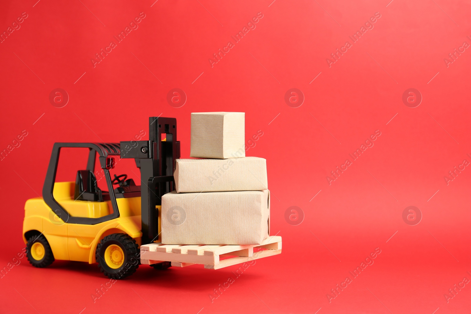 Photo of Toy forklift with wooden pallet and boxes on red background, space for text