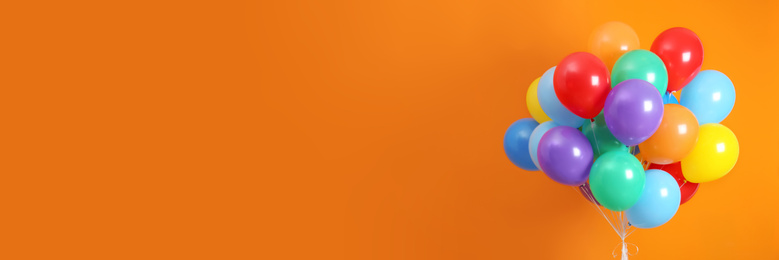 Image of Bunch of bright balloons on orange background, space for text. Banner design 