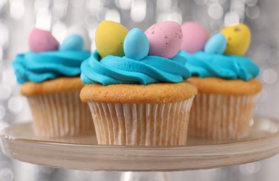 Photo of Tasty decorated Easter cupcakes on stand, closeup