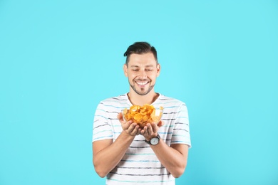 Photo of Man with bowl of potato chips on color background